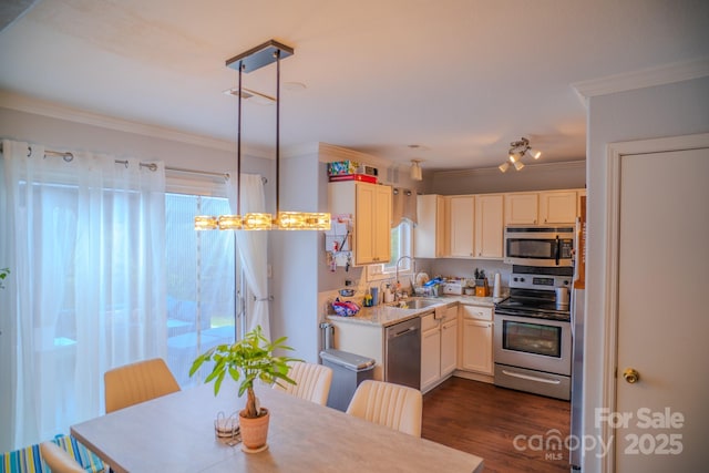kitchen with appliances with stainless steel finishes, light countertops, ornamental molding, dark wood-style flooring, and a sink