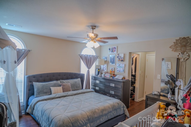bedroom featuring dark wood-style floors, a ceiling fan, and visible vents
