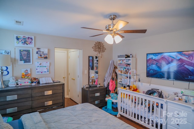 bedroom featuring a ceiling fan, visible vents, and wood finished floors