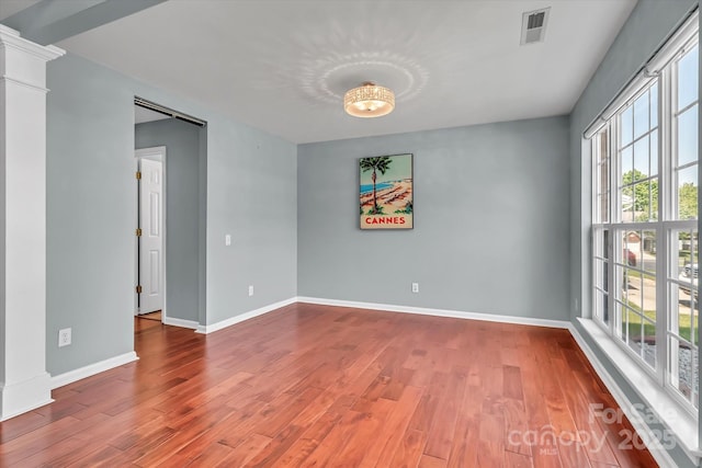 unfurnished room with baseboards, wood finished floors, and visible vents