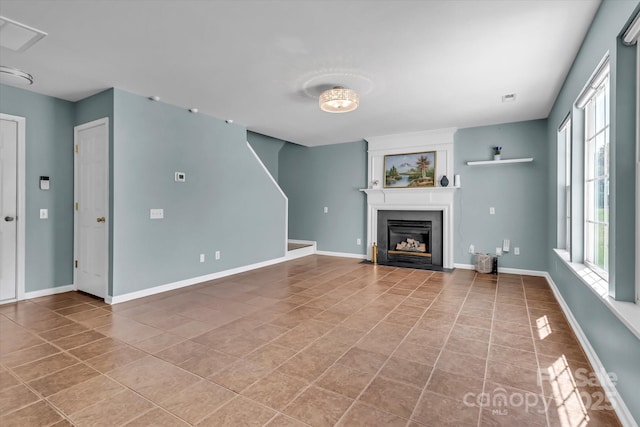 unfurnished living room with baseboards, a fireplace with flush hearth, and tile patterned flooring