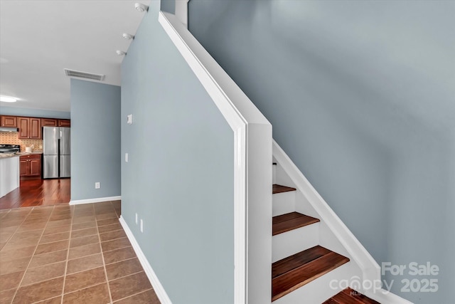 staircase with baseboards, visible vents, and tile patterned flooring