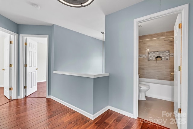 hallway featuring dark wood-type flooring and baseboards