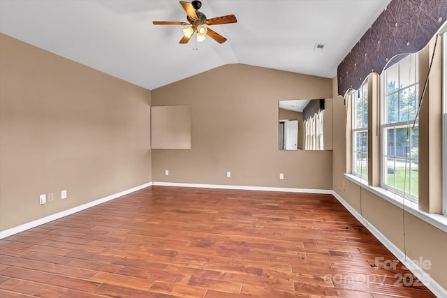 empty room with baseboards, ceiling fan, vaulted ceiling, and wood finished floors
