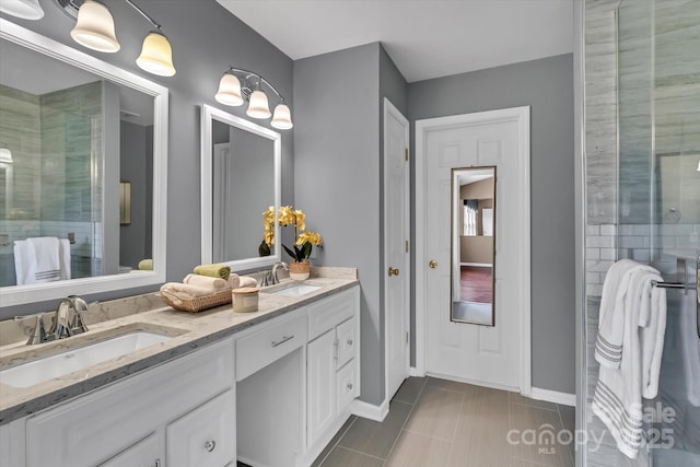 bathroom with a shower with door, double vanity, baseboards, and a sink