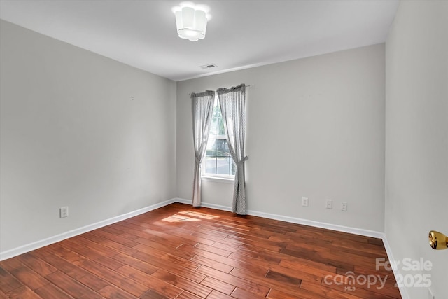 unfurnished room with visible vents, baseboards, and wood finished floors