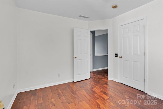 unfurnished bedroom featuring baseboards, visible vents, and wood finished floors