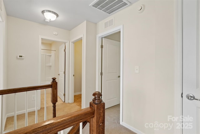 hallway featuring visible vents, baseboards, an upstairs landing, and light colored carpet