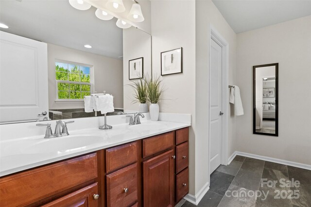 full bath featuring a sink, baseboards, and double vanity