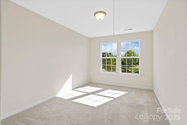 carpeted spare room with visible vents and baseboards