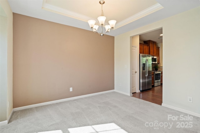 spare room with dark carpet, an inviting chandelier, crown molding, and a tray ceiling