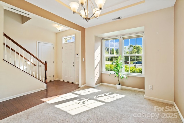 foyer entrance featuring a chandelier, baseboards, visible vents, and stairs