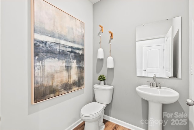 half bath featuring baseboards, toilet, and wood finished floors
