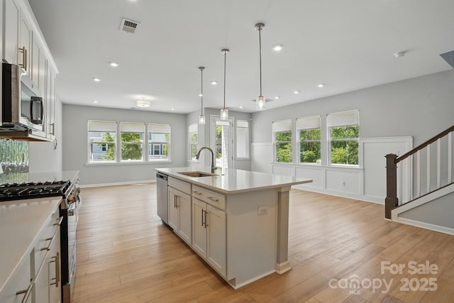 kitchen with a sink, light wood-type flooring, visible vents, light countertops, and appliances with stainless steel finishes