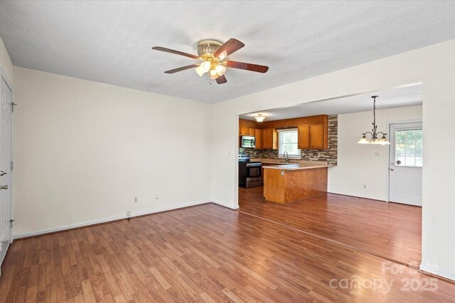 1504 Andicot Ln, Shelby, NC 28152 - unfurnished living room featuring wood finished floors, a ceiling fan, a chandelier, and healthy amount of natural light