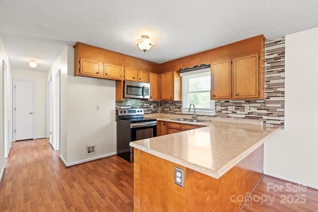 1504 Andicot Ln, Shelby, NC 28152 - kitchen featuring appliances with stainless steel finishes, a peninsula, light countertops, brown cabinets, and light wood-style flooring