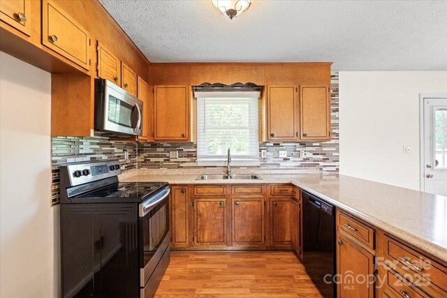 1504 Andicot Ln, Shelby, NC 28152 - kitchen featuring appliances with stainless steel finishes, light wood-style floors, brown cabinetry, light countertops, and a textured ceiling