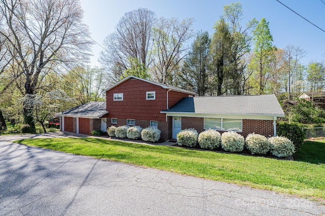 view of property exterior featuring an attached garage, driveway, brick siding, and a lawn