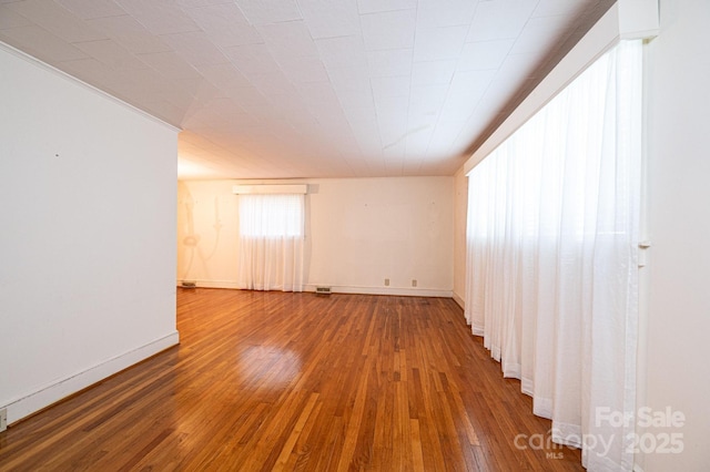 empty room with wood-type flooring and baseboards