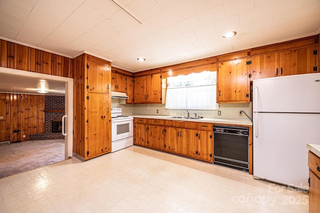 kitchen featuring brown cabinetry, under cabinet range hood, a sink, and white appliances