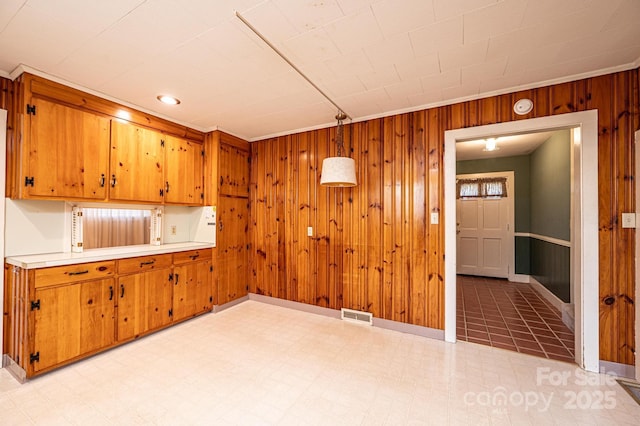 unfurnished room with visible vents, light floors, and wood walls