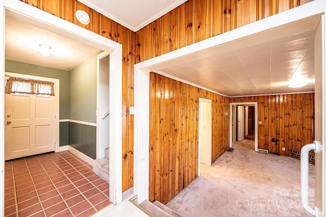 foyer entrance with wood walls, ornamental molding, and stairway