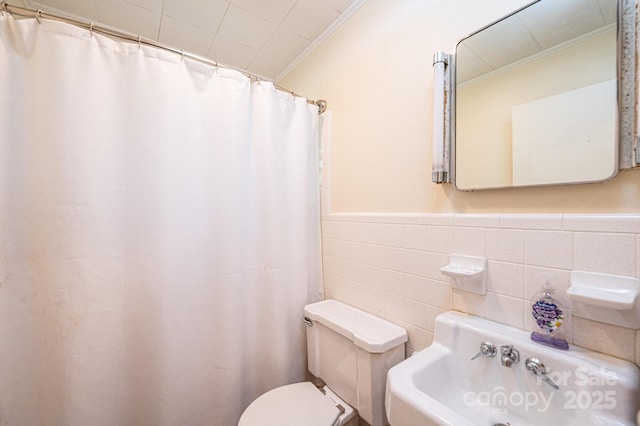 bathroom with ornamental molding, curtained shower, a wainscoted wall, toilet, and tile walls