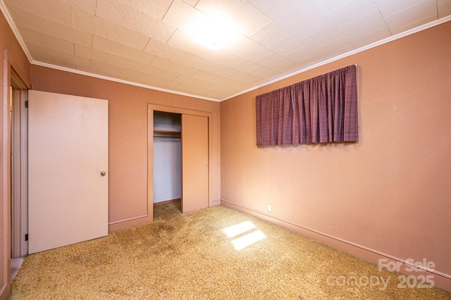 unfurnished bedroom with crown molding, a closet, baseboards, and carpet floors