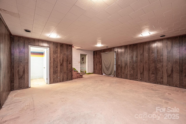 finished basement featuring wood walls and stairway