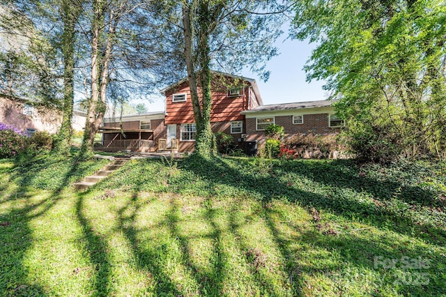 back of house with a yard, brick siding, and a wooden deck