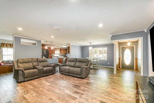 living room featuring recessed lighting, baseboards, crown molding, and light wood-style flooring