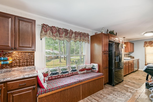 kitchen featuring stainless steel dishwasher, refrigerator with ice dispenser, brown cabinetry, light wood-style floors, and ornamental molding
