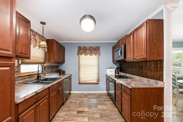 kitchen with a sink, backsplash, light wood-style floors, black appliances, and ornamental molding