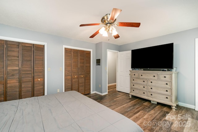 bedroom with baseboards, a ceiling fan, wood finished floors, and multiple closets