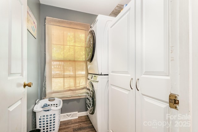 laundry room with stacked washing maching and dryer, laundry area, baseboards, dark wood-style flooring, and visible vents
