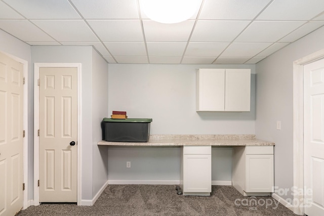 unfurnished office with built in study area, baseboards, a drop ceiling, and carpet