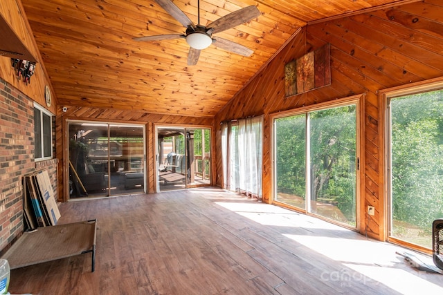 unfurnished sunroom with lofted ceiling, ceiling fan, wood ceiling, wooden walls, and wood-type flooring