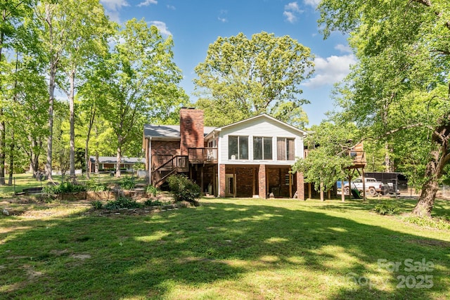 back of house featuring stairway, a chimney, a yard, brick siding, and a deck