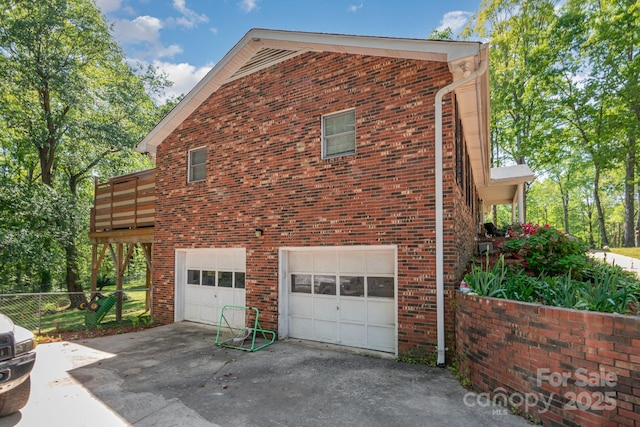 view of side of home with fence, brick siding, a garage, and concrete driveway