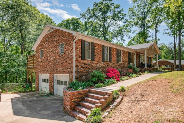 view of home's exterior featuring brick siding, driveway, fence, and a garage