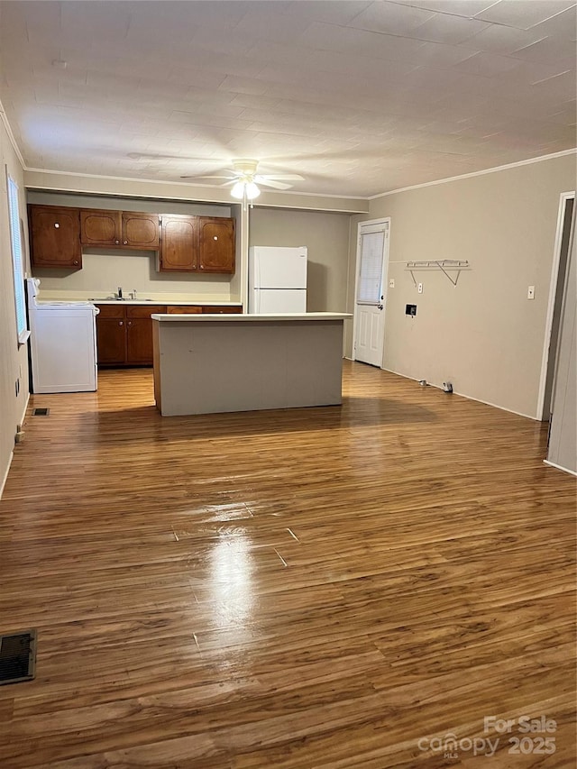 unfurnished living room with ornamental molding, visible vents, washer / dryer, and wood finished floors