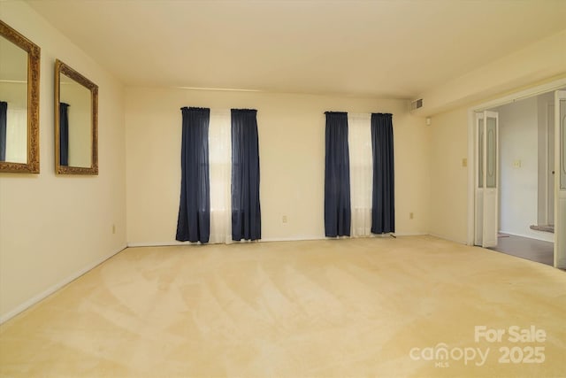 carpeted empty room featuring visible vents and baseboards