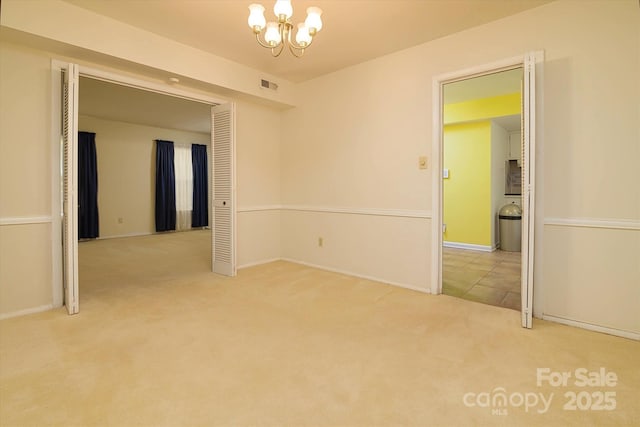 empty room with visible vents, baseboards, an inviting chandelier, and carpet floors