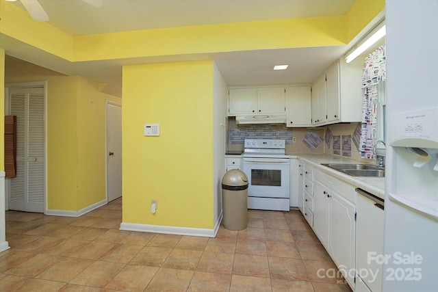 kitchen with baseboards, white appliances, white cabinets, under cabinet range hood, and a sink