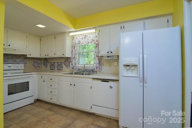 kitchen featuring tasteful backsplash, tile countertops, a sink, and white appliances