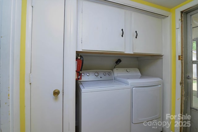 clothes washing area featuring cabinet space and washing machine and clothes dryer