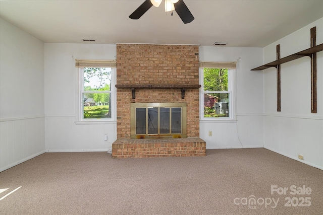 unfurnished living room featuring a fireplace, carpet flooring, ceiling fan, and a wealth of natural light