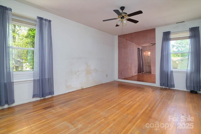 spare room with visible vents, light wood finished floors, plenty of natural light, and a ceiling fan