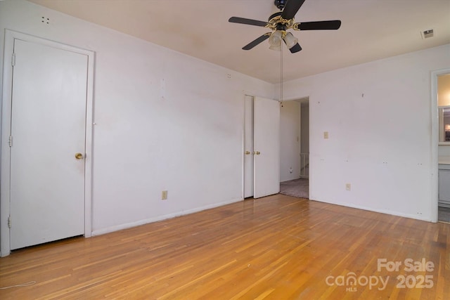 unfurnished bedroom with baseboards, light wood finished floors, ensuite bath, and visible vents