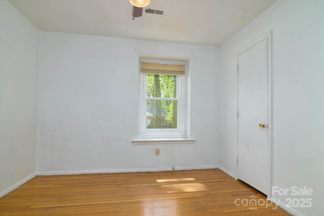spare room featuring visible vents, baseboards, a ceiling fan, and wood finished floors